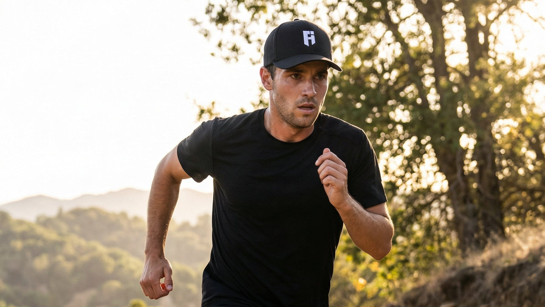 Man running on a dirt path with trees and mountains in the background